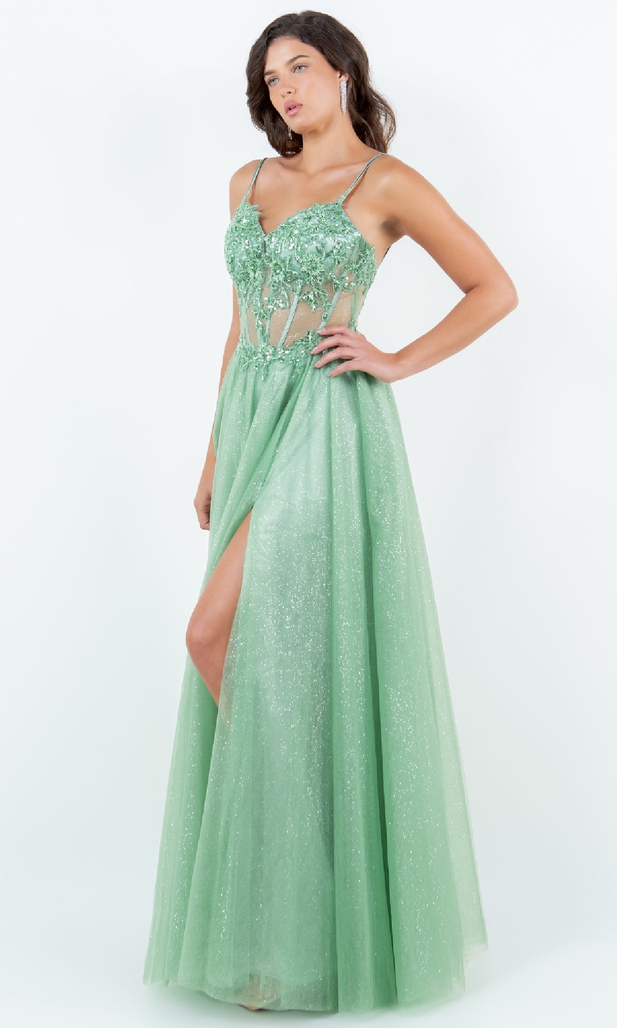 A woman models the Cinderella Couture 8238J, a sleeveless, light green glitter prom dress featuring an A-line silhouette, fitted floral applique bodice, sheer panels, and a thigh-high slit.